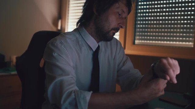 Portrait of concentrated businessman thinking and waiting in dark office interior, worried and concerned.