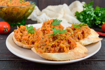 Squash caviar on a crispy baguette on a dark wooden table. Sandwiches with stewed vegetables. Vegan appetizer.
