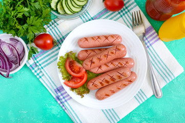 Delicious juicy grilled sausages on a plate, vegetables, ketchup and mustard on a bright...