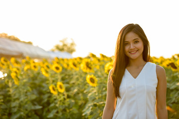 Young happy Asian woman smiling in the field of blooming sunflow