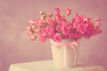 bouquet of pink roses in a mint-colored pot on a blurred background. toned photo