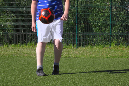 chubby boy juggling a soccer ball on the soccer field with artificial turf - Powered by Adobe