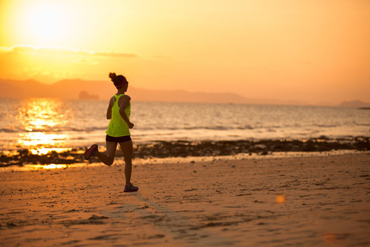 Young woman running at sunset sandy beach