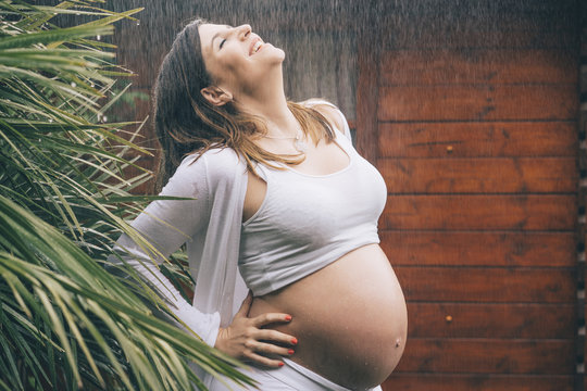 Beautiful pregnant woman posing in the rain..