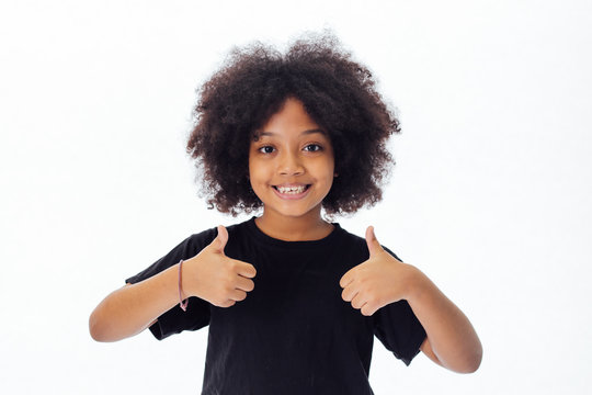 Adorable and cheerful African American kid with afro hairstyle giving thumbs up isolated over white background
