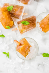 Frozen refreshing drinks, summer cocktail popsicles recipe, cuba libre, cold sweet tea or coffee, with ice, lime and mint leaves on white marble background copy space