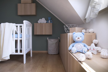 Stylish scandinavian newborn baby room with toys, star lamp and teddy bear. Modern green background wall. 