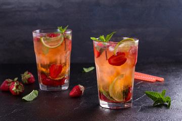 Strawberry mojito cocktail with berries, lime, mint and ice, black background. Summer berry cocktail