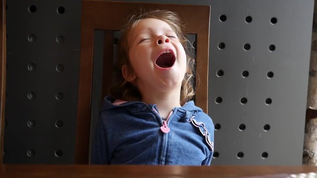 Little child girl portrait yawning during sitting in a restaurant pizzeria