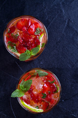 Strawberry mojito cocktail with berries, lime, mint and ice, black background. Summer berry cocktail. View from above, top studio shot