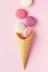 Flatlay of pastel cake macaron or macaroon and sweet cones over pastel pink background. Top view with space for your text