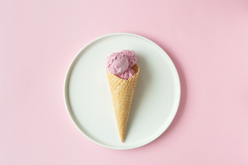 Flatlay of pink ice cream scoops, sweet cones and peonies over pastel pink background. Top view with space for your text