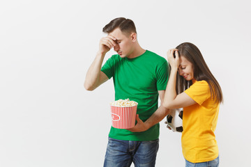 European upset couple, woman, man, football fans in yellow green t-shirt cheer up support team with soccer ball bucket of popcorn isolated on white background. Sport, family leisure, lifestyle concept