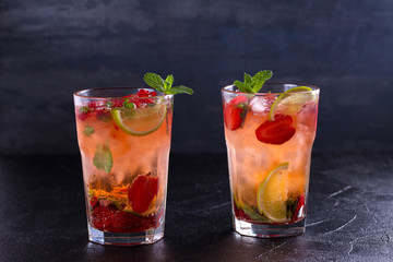 Strawberry mojito cocktail with berries, lime, mint and ice, black background. Summer berry cocktail