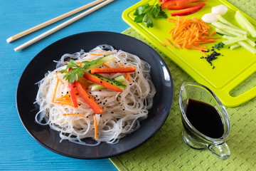 cellophane noodles on a plate on a wooden table with vegetables salad cooking