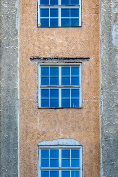Front view of three symmetrical windows on a stone city building with colorful texture.