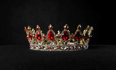 portrait of a beautiful jewelled ruby, diamond and golden crown, photographed on a black studio...