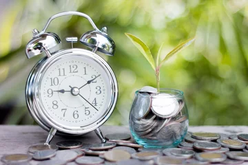 Fotobehang Close up of time and money with green bokeh background, Save money for prepare in the future. © Tinnakorn