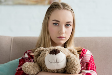 close-up portrait of beautiful teen girl embracing her teddy bear and looking at camera