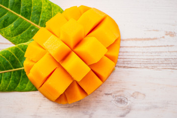 Fresh and beautiful mango fruit with sliced diced mango chunks on a light wooden background, copy space(text space), blank for text, top view.