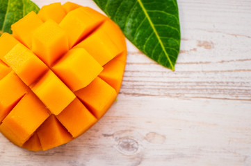 Fresh and beautiful mango fruit with sliced diced mango chunks on a light wooden background, copy space(text space), blank for text, top view.