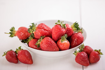 red ripe strawberries on white background in a bowl