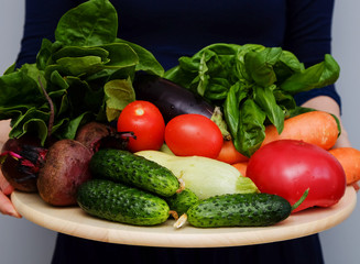 Woman's hands holding tray with fresh colorful vegetables. Healthy food concept.