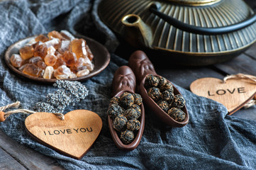A Cup of brewed black tea. Two ceramic spatulas with caramel sugar and Rolled leaves in a large pearl. Chinese tea from Yunnan. Bi Lo Chun