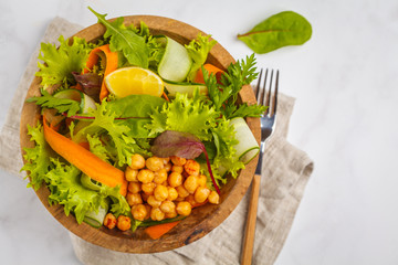 Summer bright vegetable salad with chickpeas in a wooden bowl. Healthy vegan food concept.