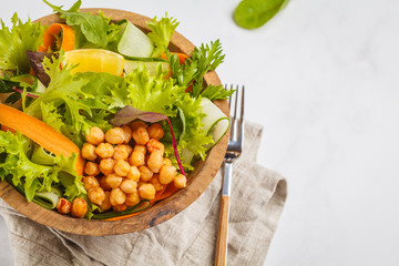 Summer bright vegetable salad with chickpeas in a wooden bowl. Healthy vegan food concept.