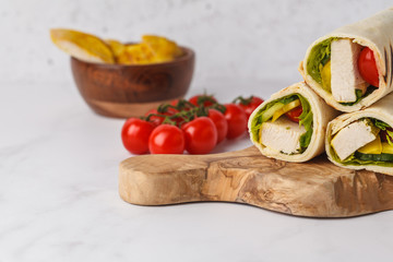 Grilled tortilla wraps with chicken and vegetables  on wooden board, copy space