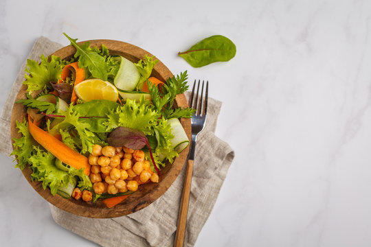Summer bright vegetable salad with chickpeas in a wooden bowl. Healthy vegan food concept.
