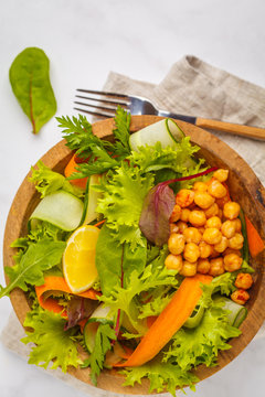 Summer bright vegetable salad with chickpeas in a wooden bowl. Healthy vegan food concept.