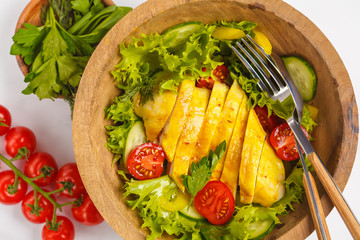 Grilled chicken salad with vegetables in a wooden bowl on a white background. Healthy balanced diet concept.