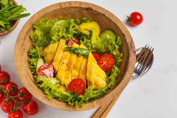 Grilled chicken salad with vegetables in a wooden bowl on a white background. Healthy balanced diet concept.