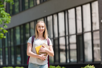 happy teen student girl with books walking on street