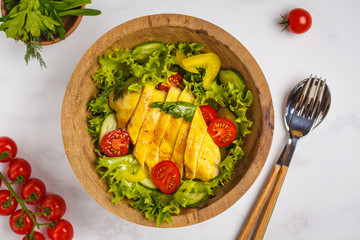Grilled chicken salad with vegetables in a wooden bowl on a white background. Healthy balanced diet concept.