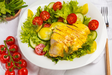 Grilled chicken salad with vegetables in a white plate on a white background. Healthy balanced diet concept.