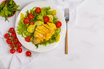 Grilled chicken salad with vegetables in a white plate on a white background. Healthy balanced diet concept.
