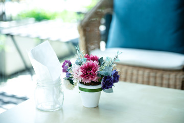 Fake flower in white pot with white tissue on table