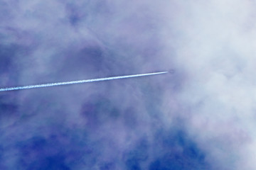 The passenger plane flies away beyond the horizon The plane flies over the clouds during the sunset Rear view of aircraft.