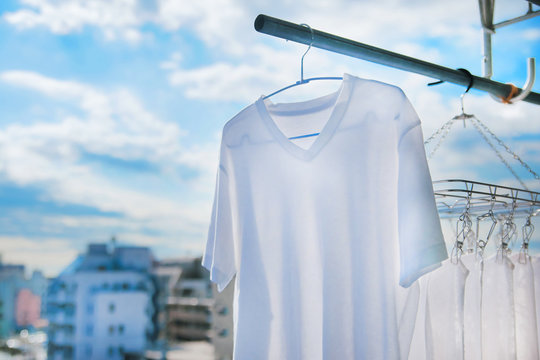 晴れた日に白いタオルとTシャツを洗濯して干す様子。