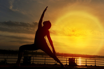 Silhouette of Woman train Yoga on lawn yard along River Mountain during SunRise