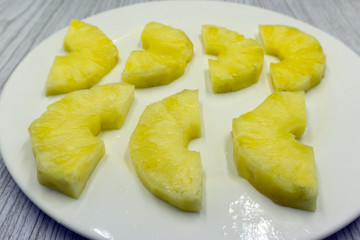Circles cut peeled pineapple slices on yellow background close-up .