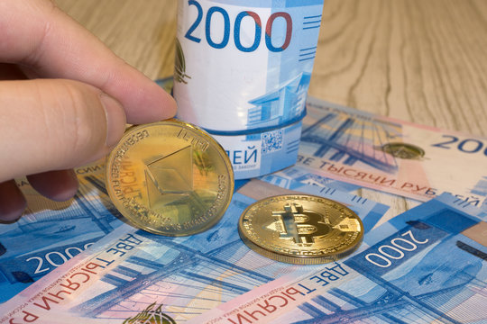 Gold krypto coins bitcoin BTC, paper notes of Russian rubles. Metal coins are laid out in a background to each other, close-up view from top, crypto currency exchange of money.