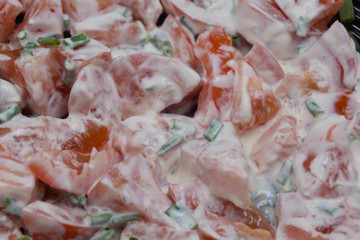 A white plate with slices of roma tomatoes with one slice being skewered with fork plus a bowl of ranch dressing to the side.