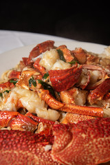 Stir-fried lobster with ginger and green onions on top of a bed of noodles