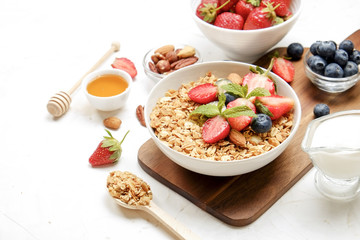 Serving option of granola bowl with mix of nuts, cereals, fruits and berries, greek yogurt. Healthy vegetarian breakfast, organic strawberry, blueberry, mint, almond. Close up, top view, background.