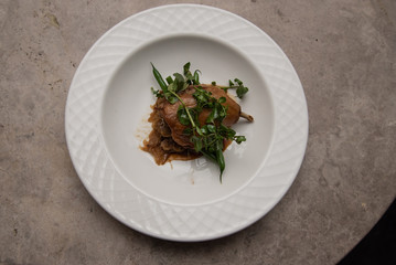 Fine food: Roast duck with watercress, green beans and caramelized onions on a white plate