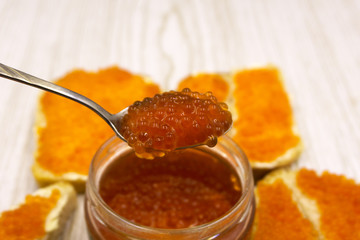 Sandwiches with imitation red caviar and butter close-up on wooden cutting board on wooden table .